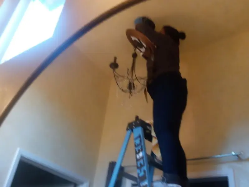 Electrician installing a chandelier in a Millbury residence